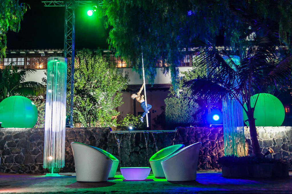 Artista de circo suspendido en telas iluminado en evento nocturno en Tenerife.