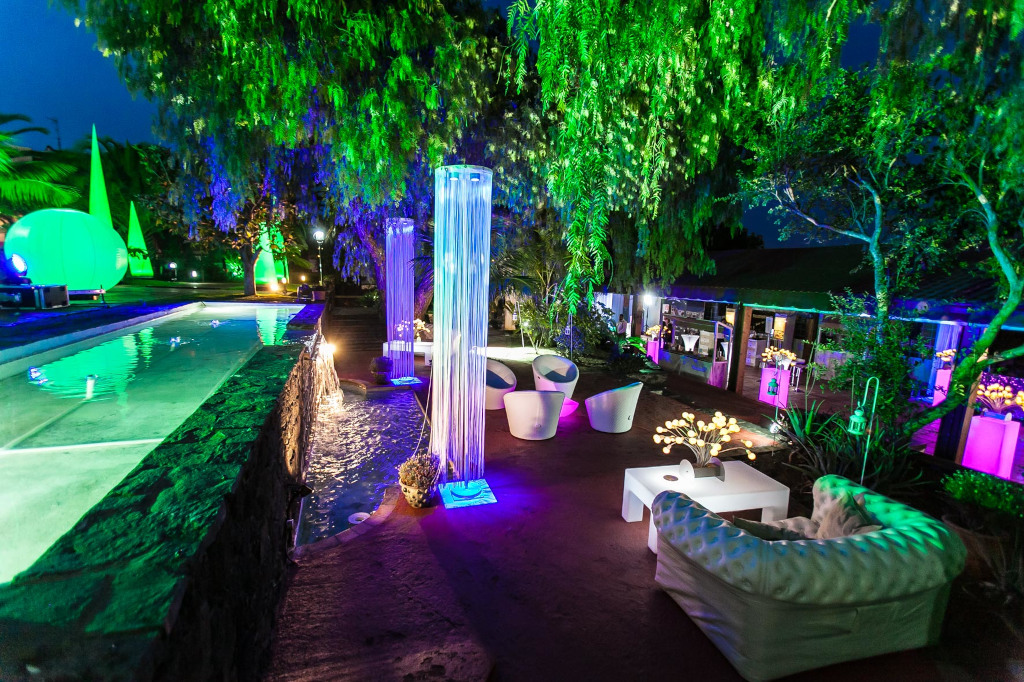 Terraza iluminada en Tenerife con luces verdes y violeta sobre muebles y vegetación.