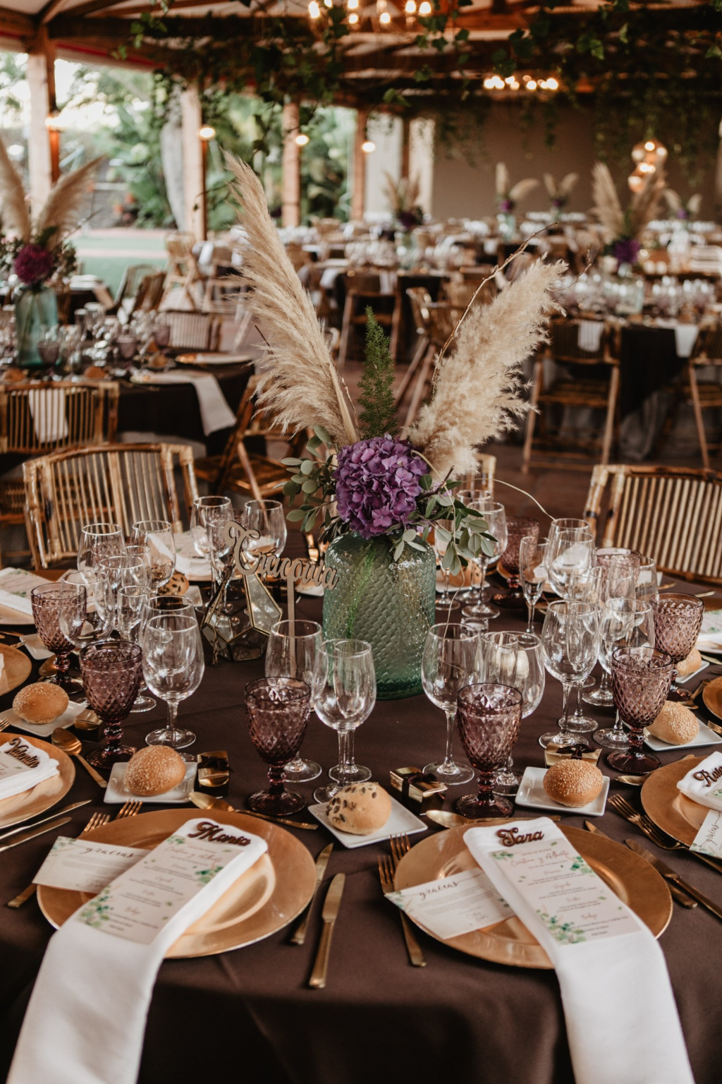 Mesa de banquete elegantemente decorada en Tenerife con flores, copas y menús personalizados.