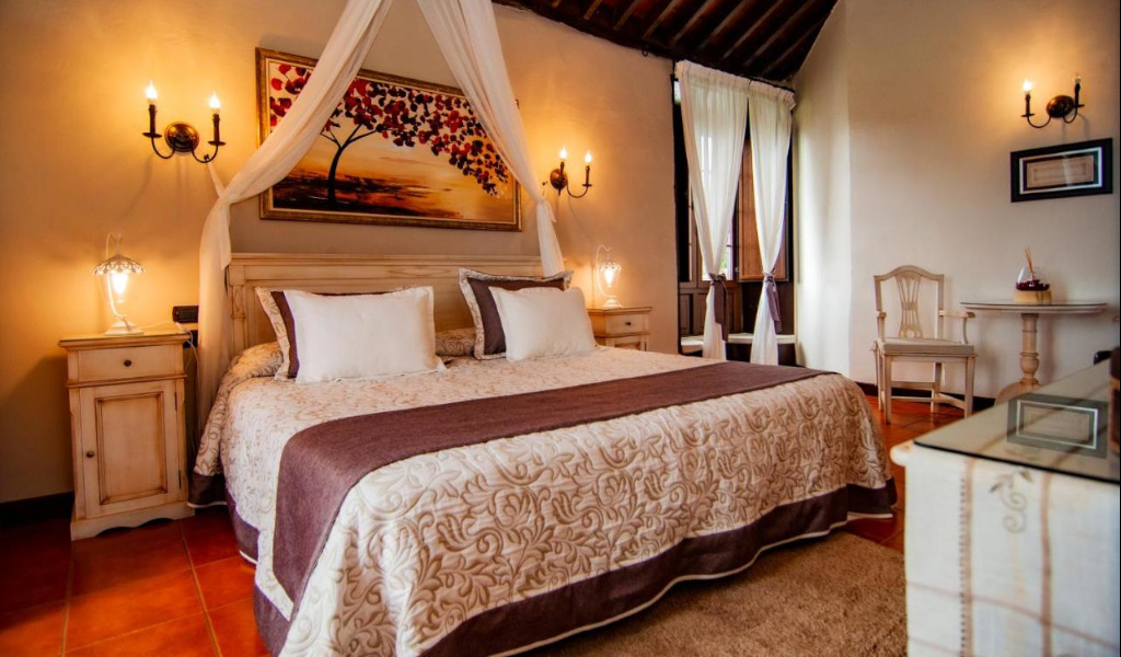 Habitación de hotel rústica en Tenerife con cama doble y decoración clásica.