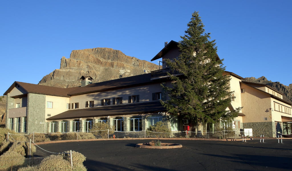 Edificio con fondo montañoso y árbol grande en El Teide, Tenerife.