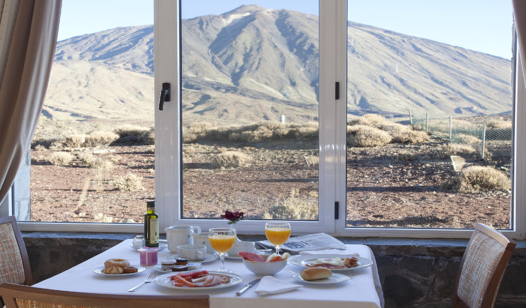 Desayuno servido con vista al Teide desde un ventanal en Tenerife.