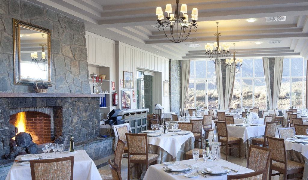 Restaurante en Tenerife con chimenea y mesas elegantemente dispuestas.