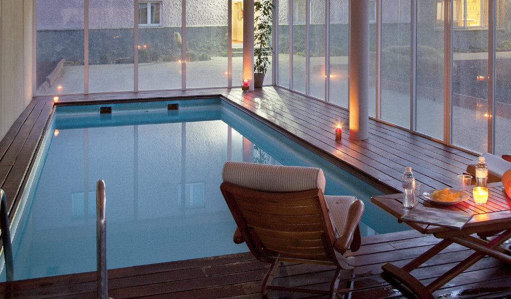 Piscina interior con sillas, mesa y velas en hotel de Tenerife.