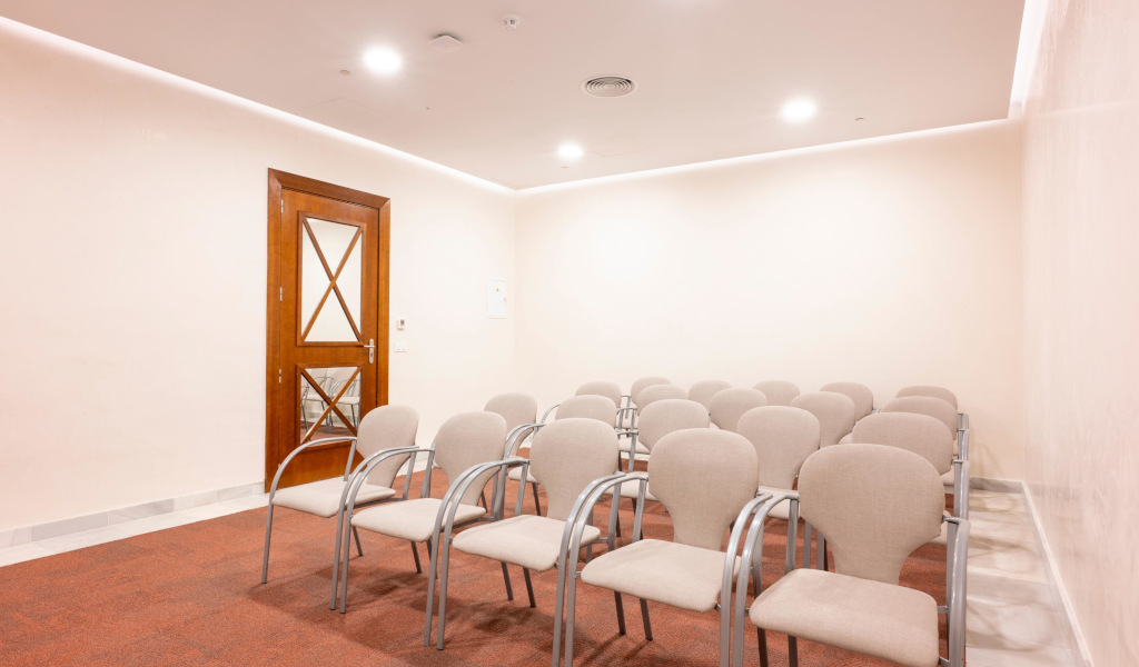 Sala de conferencias vacía con sillas y puerta de madera en Tenerife.