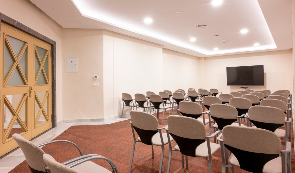 Sala de conferencias en Tenerife con sillas y pantalla grande.