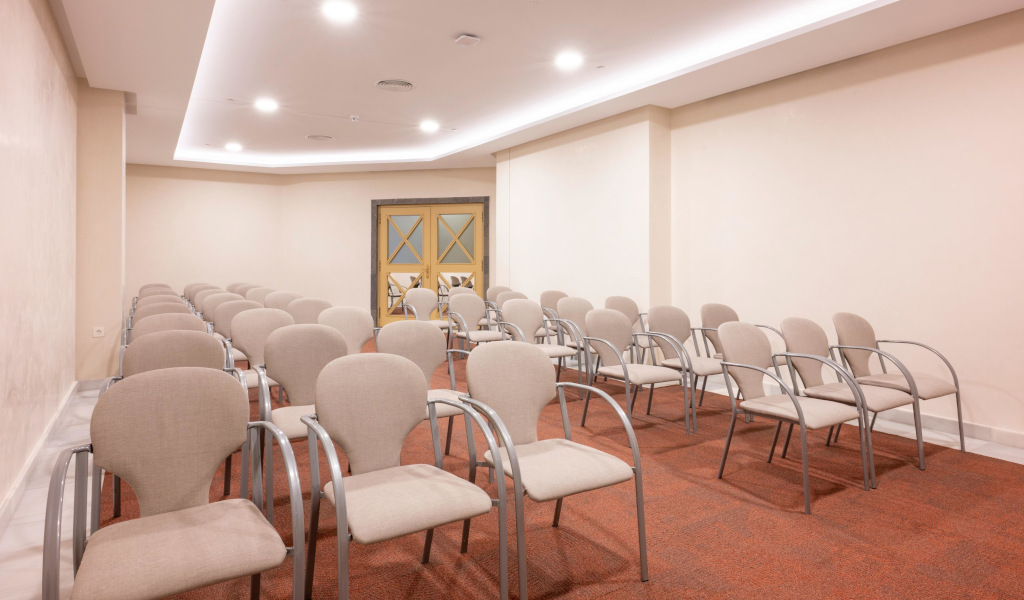 Sala de conferencias vacía con filas de sillas beige en Tenerife.
