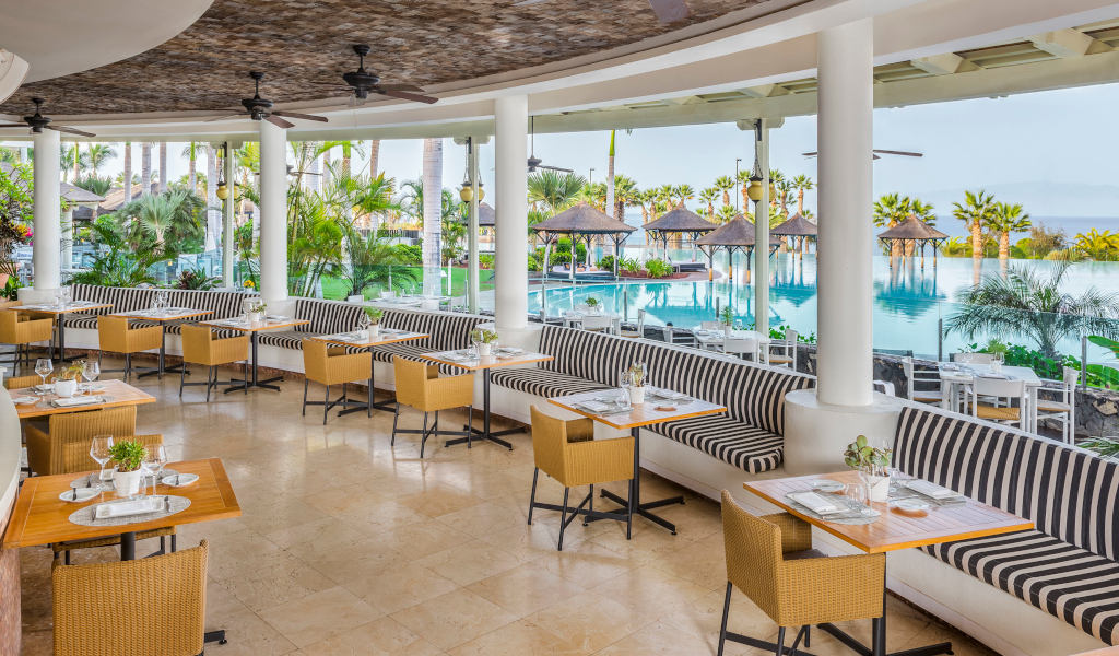 Restaurante con mesas y sillas junto a piscina en Tenerife.