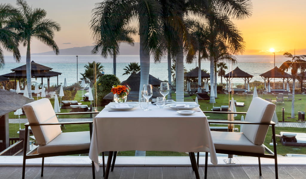 Mesa en terraza con vista al mar al atardecer en Tenerife.