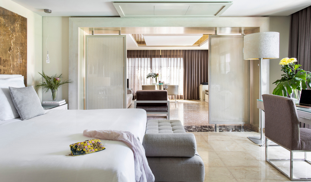 Habitación moderna de hotel en Tenerife con cama y sala de estar al fondo.