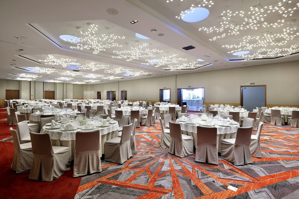 Salón de eventos con mesas redondas y sillas blancas en Tenerife.