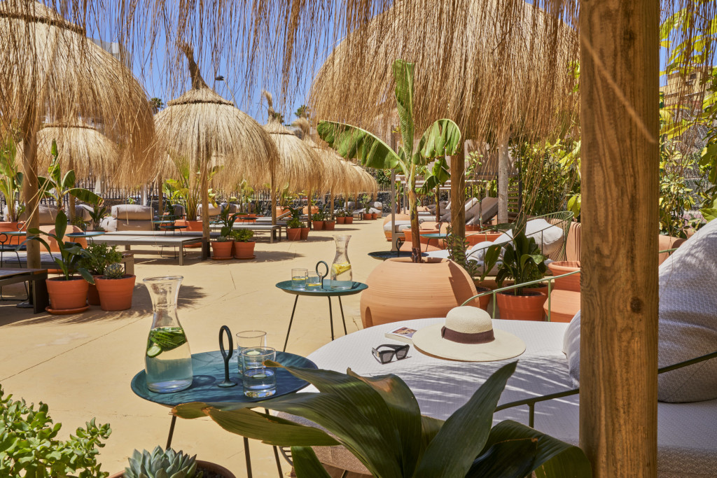 Terraza con sombrillas de paja y plantas en un patio en Tenerife.