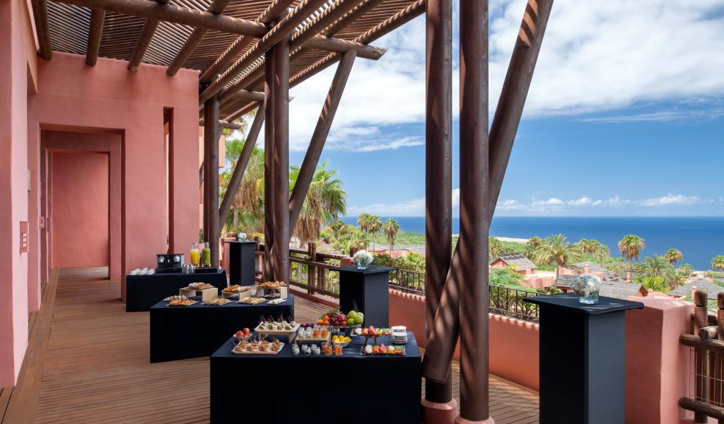 Mesa de bocadillos y jugos en terraza con vista al mar en Tenerife.