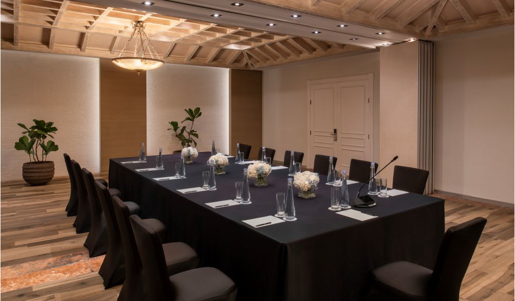 Sala de reuniones con mesa cuadrada, sillas y decoración floral en Tenerife.