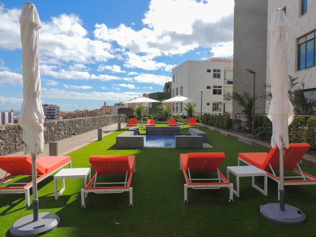 Tumbonas y sombrillas en terraza con vista urbana en Santa Cruz de Tenerife.