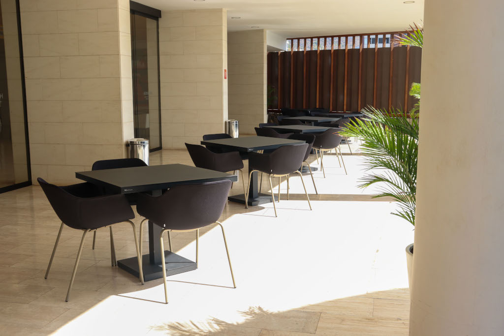 Terraza con mesas y sillas negras en Tenerife, con luz natural y plantas decorativas.