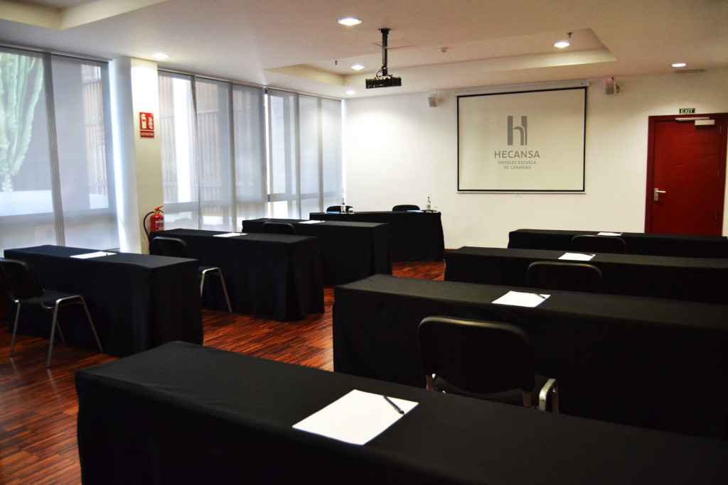 Aula de conferencias preparada con mesas y sillas en Hecansa, Tenerife.