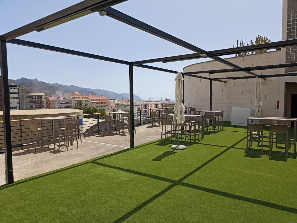 Terraza con mesas y sillas, vista a Santa Cruz de Tenerife al fondo.