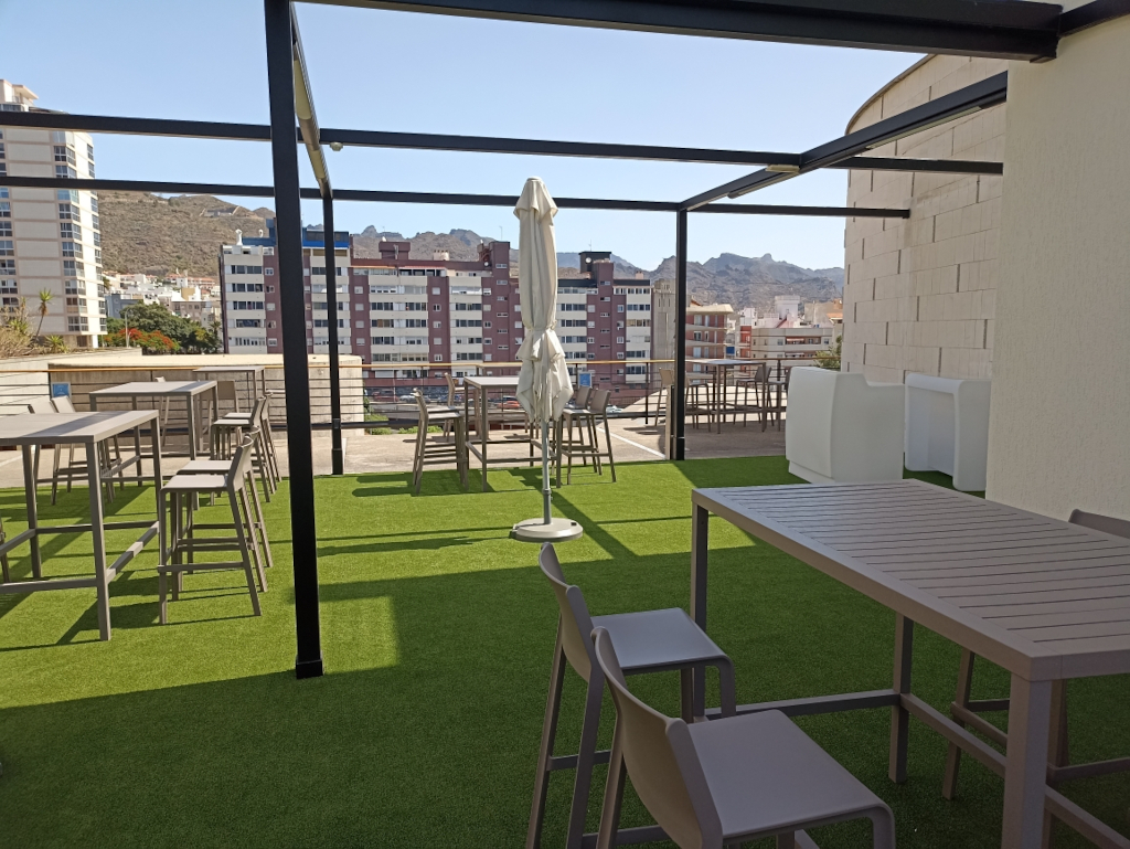 Terraza con mesas y sillas con vista a edificios en Santa Cruz de Tenerife.