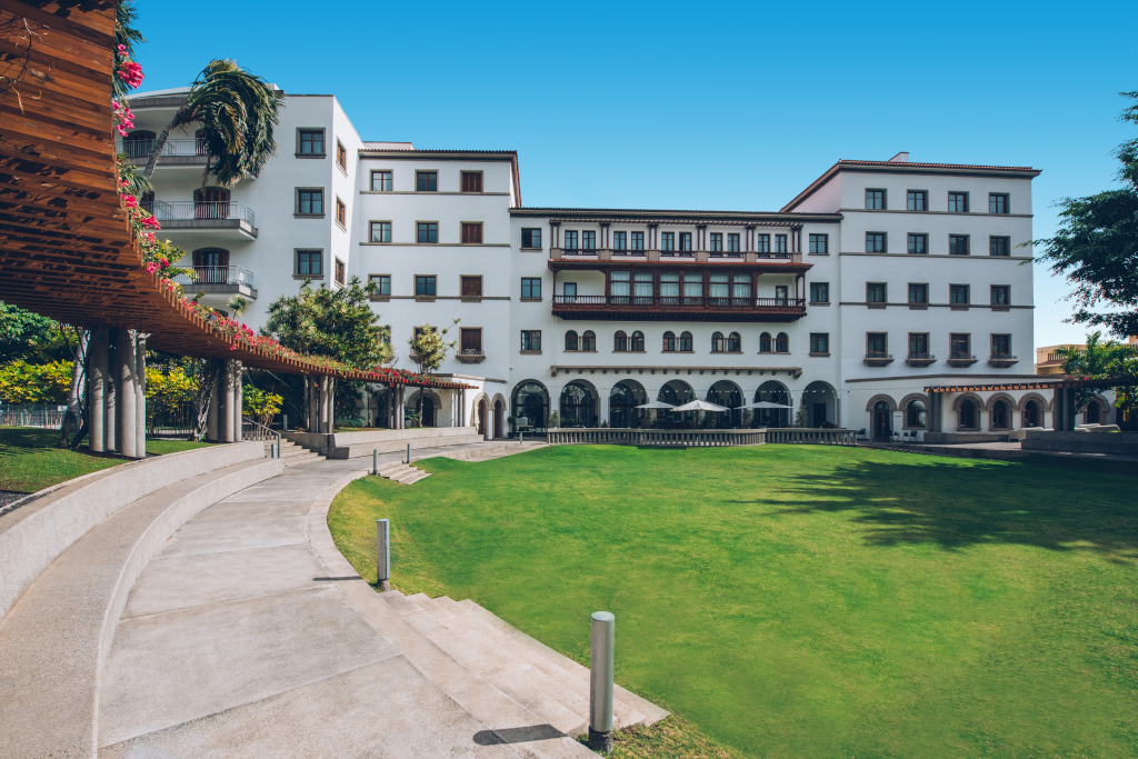 Edificio blanco con jardín verde y pérgola en Santa Cruz de Tenerife.