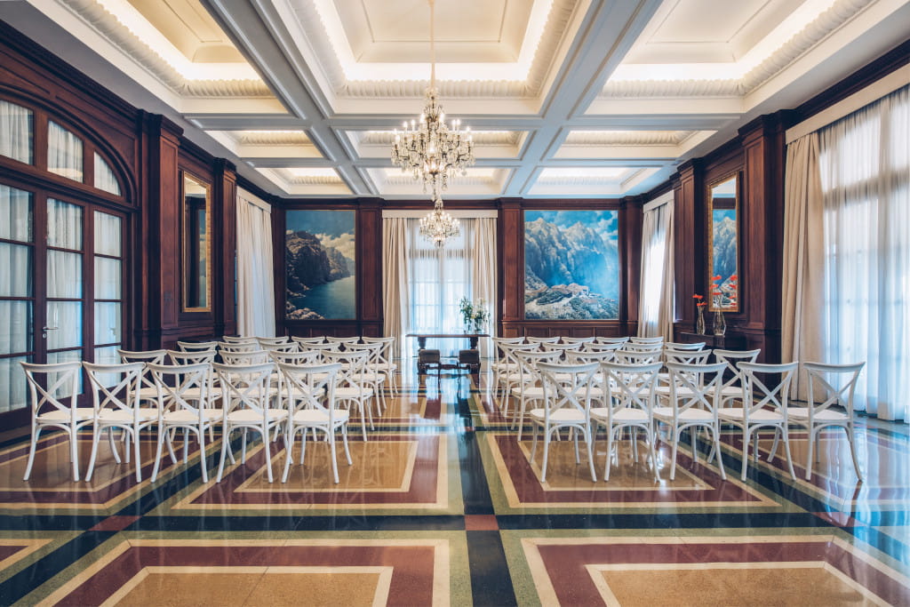 Sala de eventos con sillas blancas y cuadros de paisajes en Tenerife.