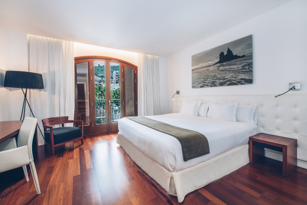 Habitación moderna con cama doble, escritorio y ventana con vistas en Tenerife.
