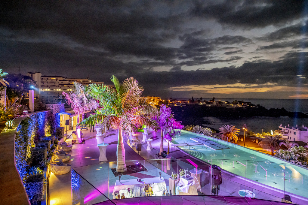 Terraza iluminada con piscina y vista al mar en Tenerife al atardecer.