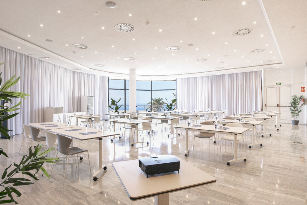 Sala de conferencias con mesas y sillas en Tenerife, vista al océano.