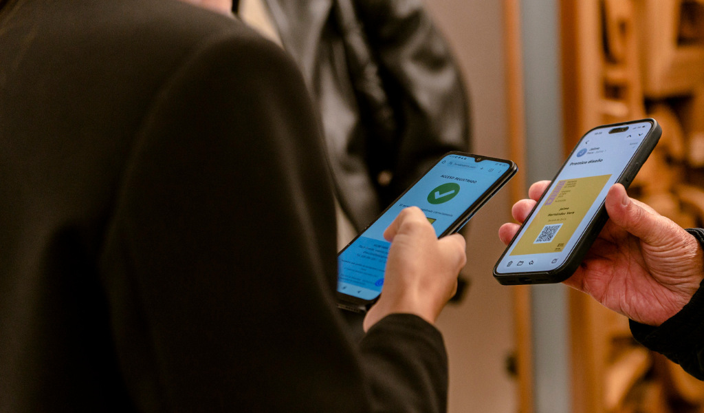 Dos personas verificando códigos QR en pantallas de teléfonos móviles.