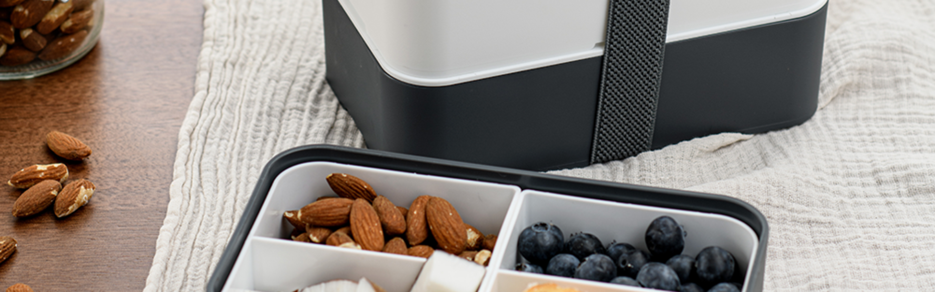 Caja bento con almendras, arándanos y más en una mesa de Tenerife.