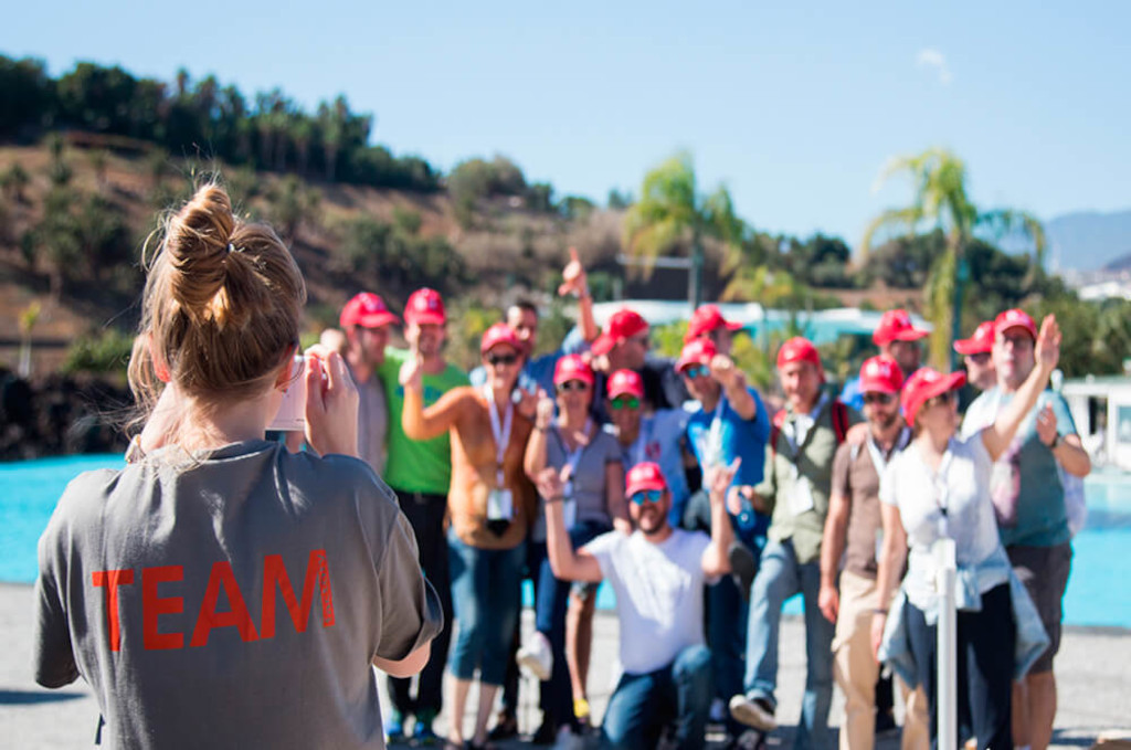 Grupo de personas con gorras rojas posando junto a una piscina en Tenerife.