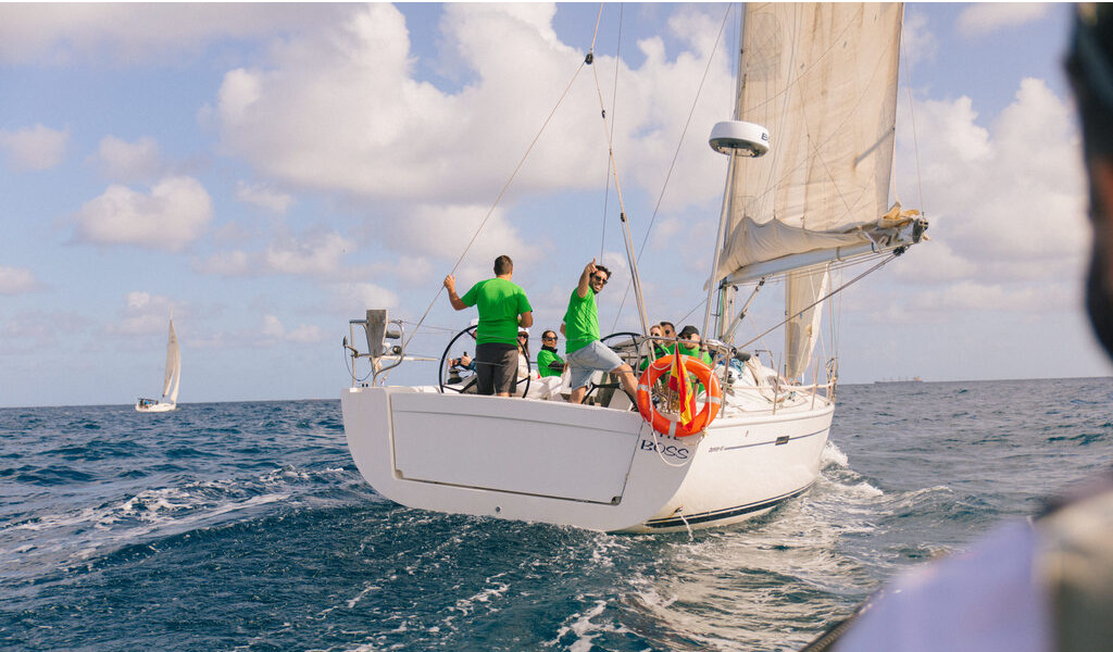 Barco a vela en el mar cerca de la costa de Tenerife bajo un cielo parcialmente nublado.