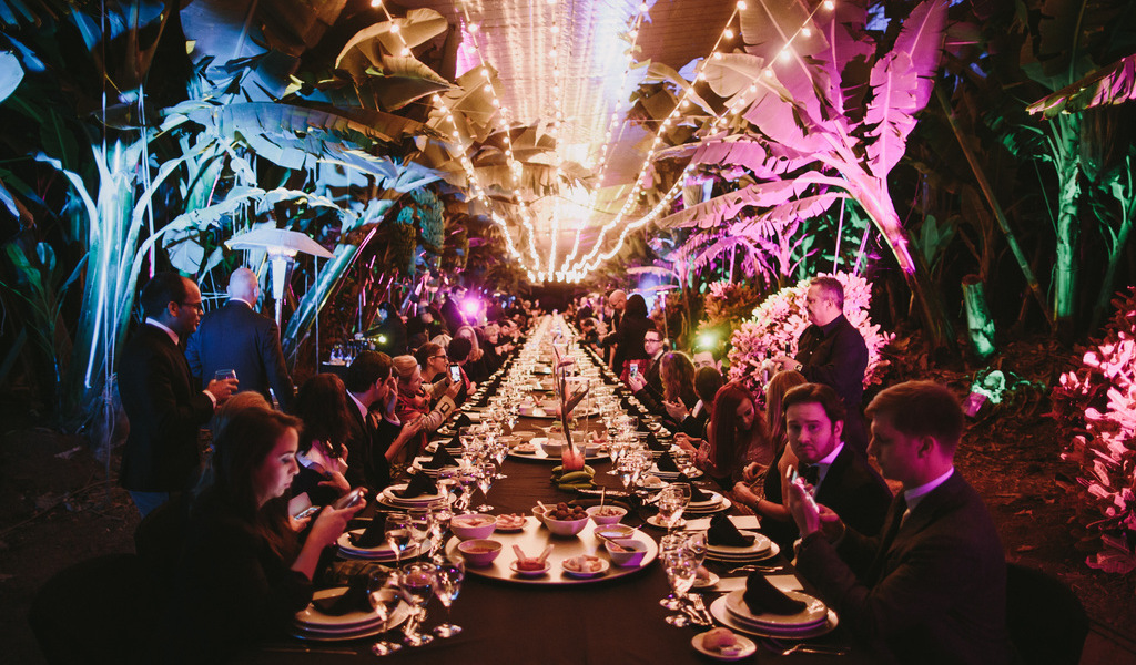 Cena al aire libre con luces y personas sentadas en una larga mesa en Tenerife.