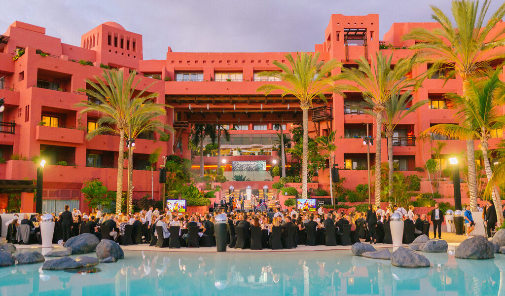 Evento al aire libre con personas en Santa Cruz de Tenerife frente a un edificio color terracota.