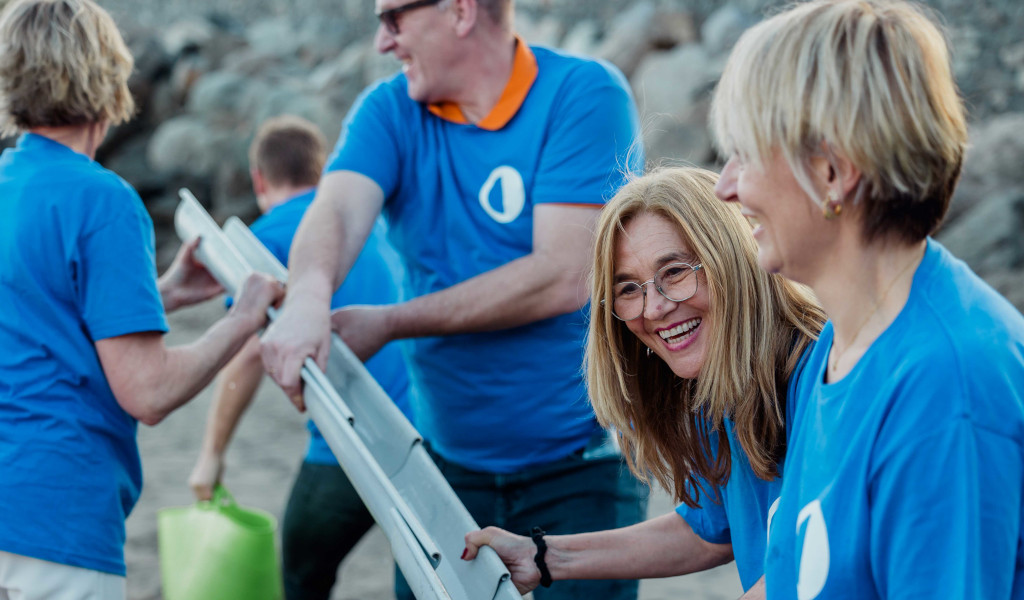 Personas en camiseta azul colaboran en una actividad en la playa de Tenerife.