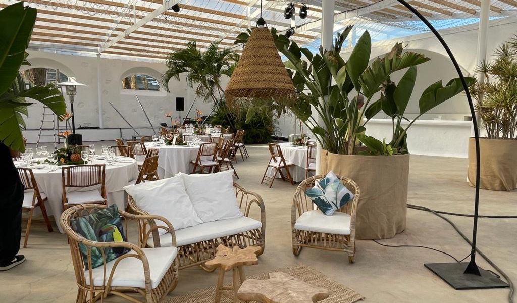 Espacio decorado con mesas y sofás de mimbre en un evento en Tenerife