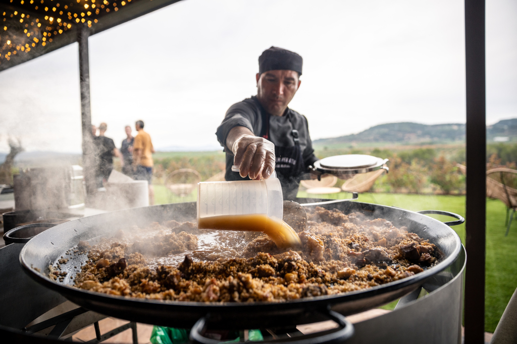 Cocinero vertiendo caldo en una paella grande al aire libre en Tenerife.