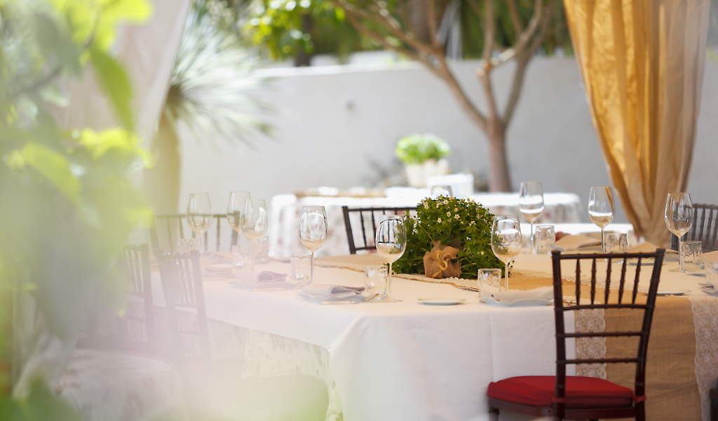 Mesa preparada con copas y centro de flores en restaurante al aire libre en Tenerife.