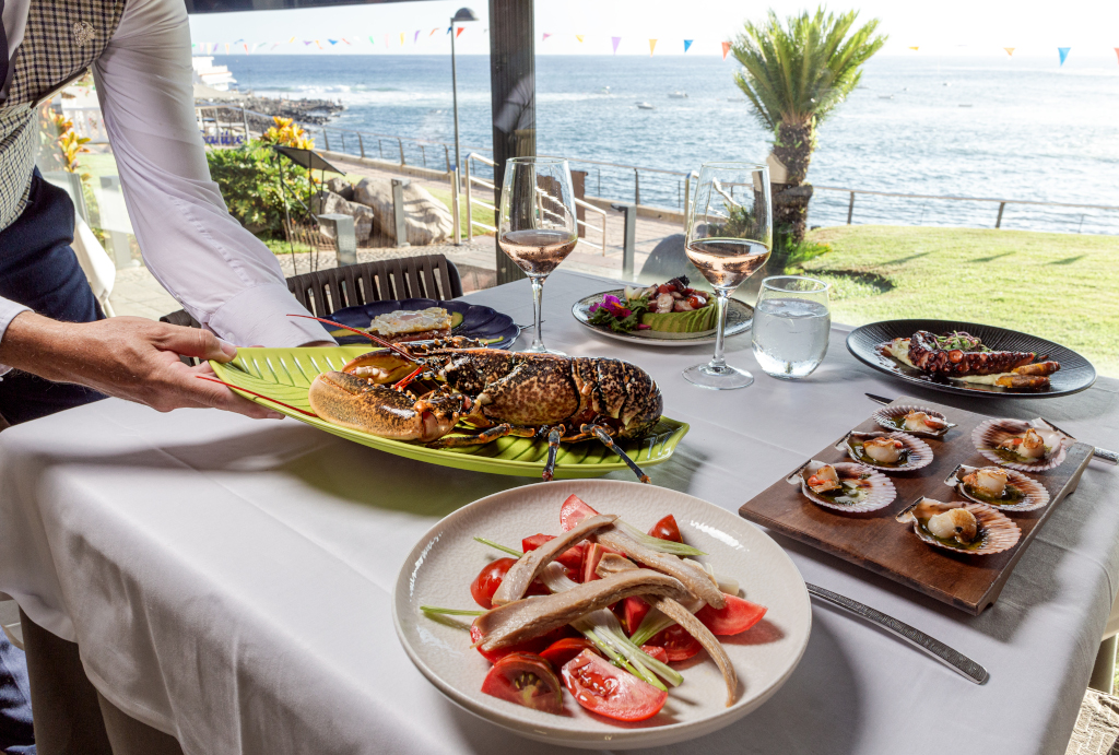 Platos de mariscos y vino en restaurante con vista al mar en Tenerife.
