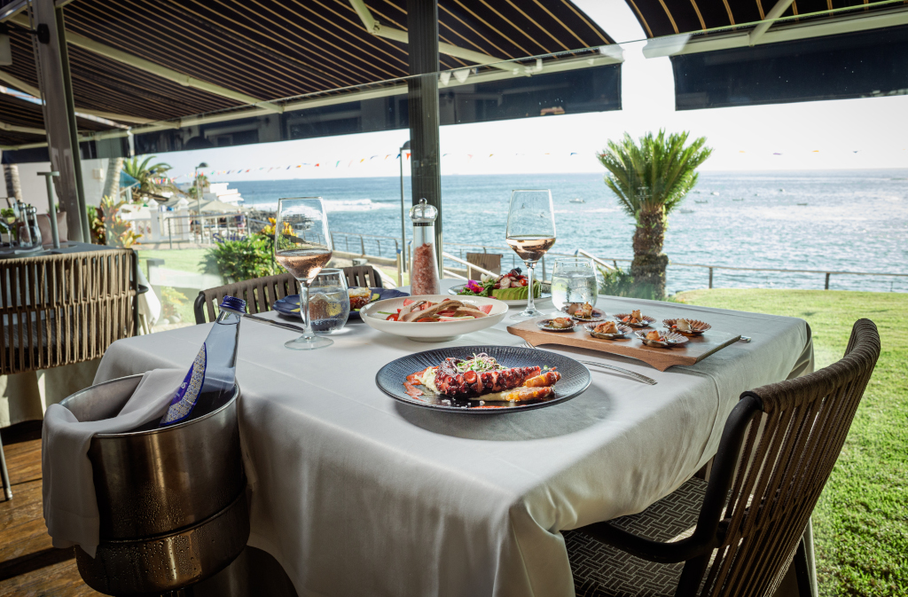 Mesa de restaurante con platos gourmet y vista al mar en Tenerife.