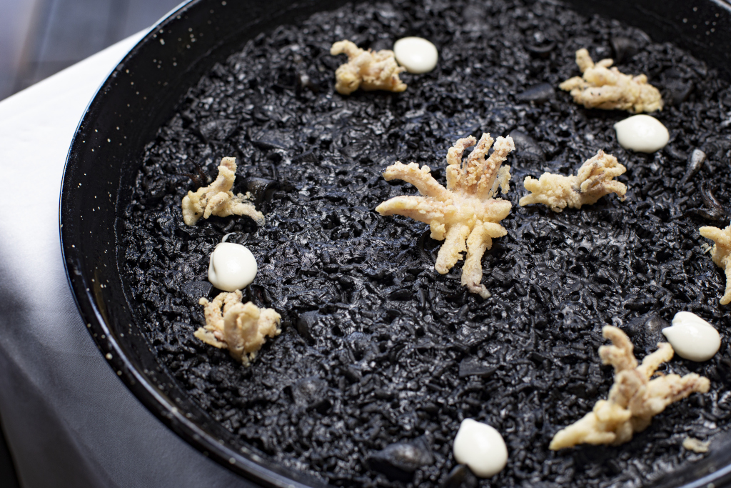 Arroz negro con calamares y alioli servido en un plato en Tenerife.