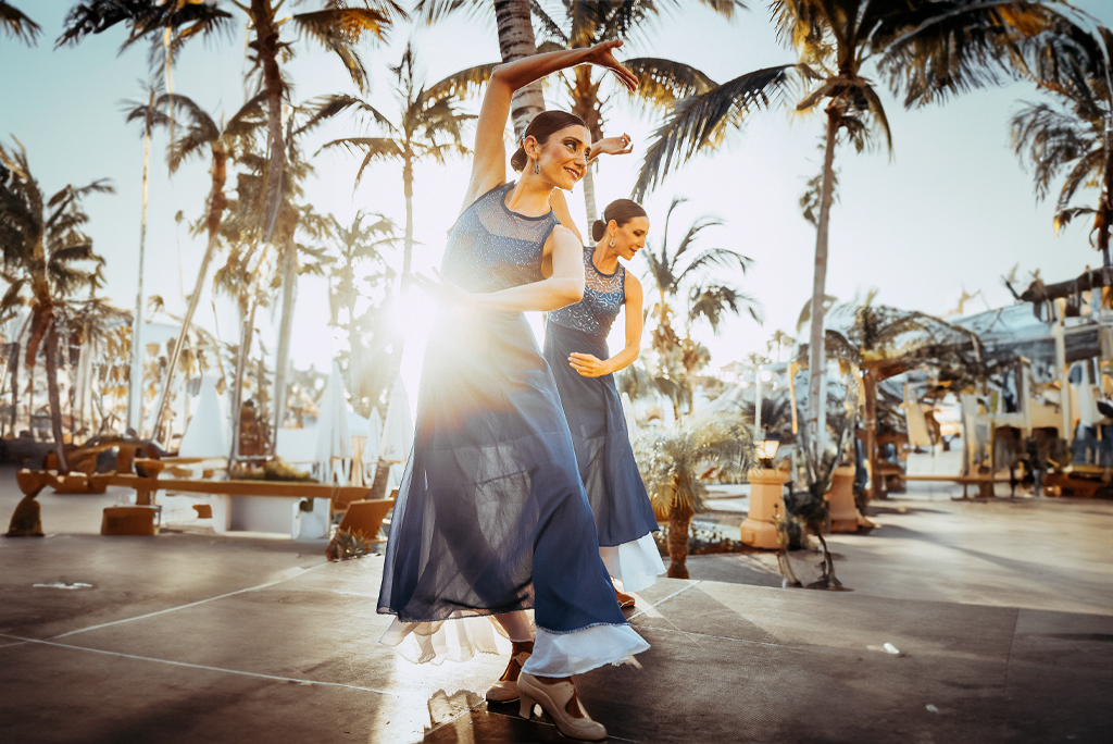 Bailarinas actuando entre palmeras al atardecer en Tenerife.
