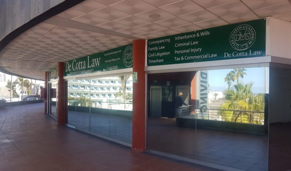 Entrada de la oficina De Cotta Law en Tenerife con cartel de servicios legales.