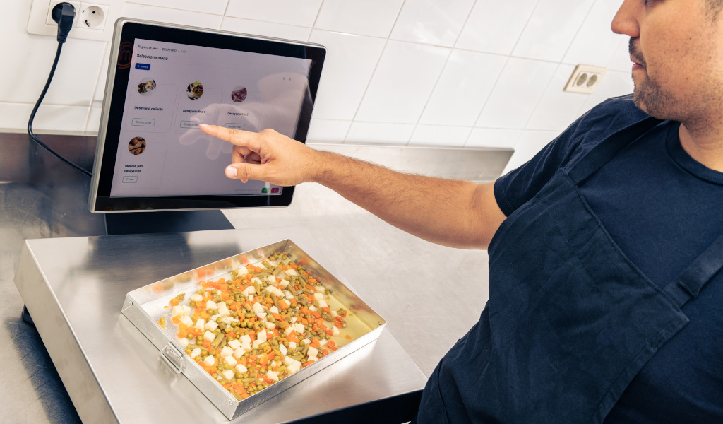 Persona seleccionando receta en pantalla táctil en cocina de Tenerife.