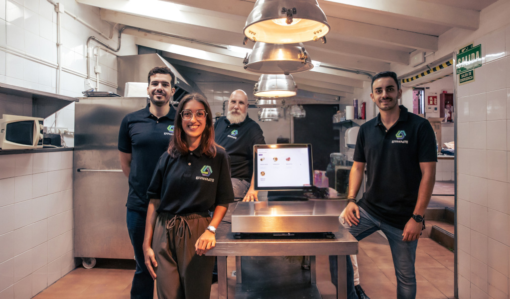 Equipo de trabajo en una cocina industrial en Tenerife, con pantalla de menú.