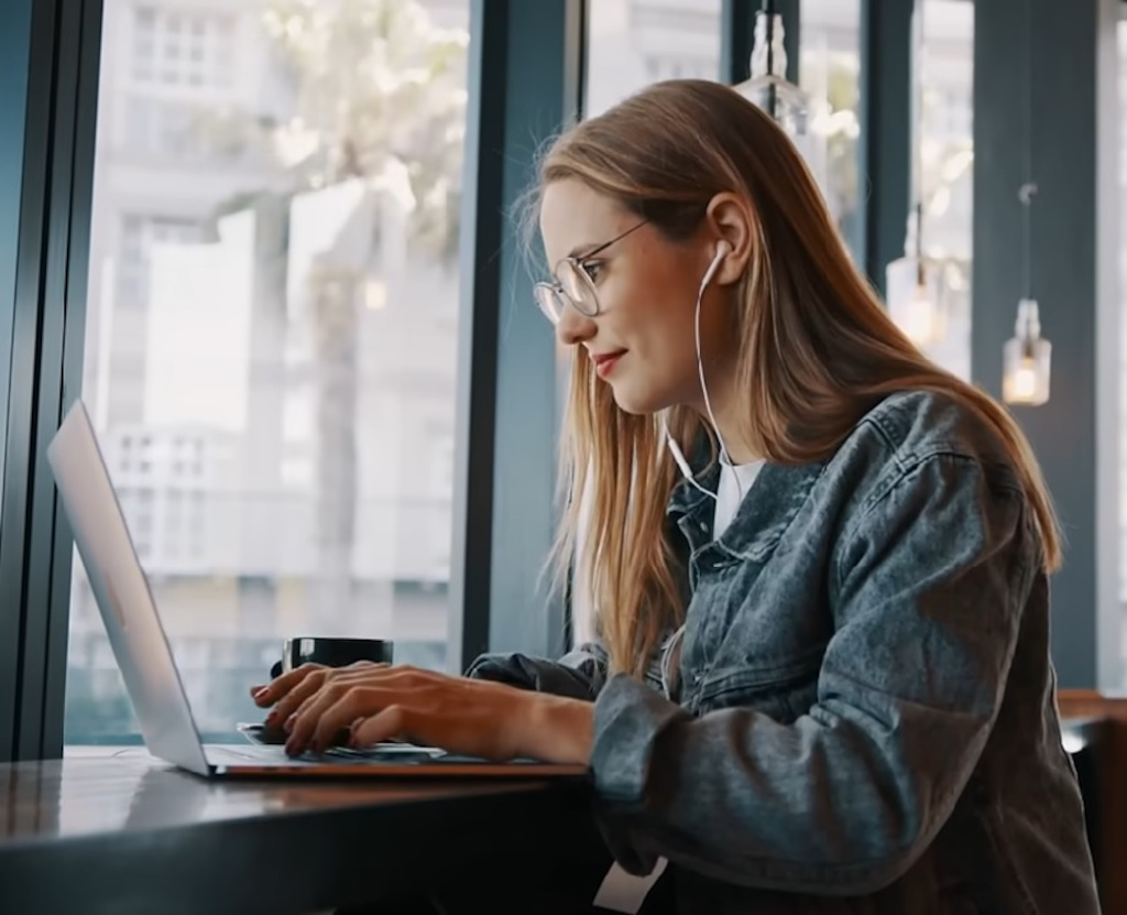 Persona con audífonos usando computadora portátil en cafetería en Tenerife.