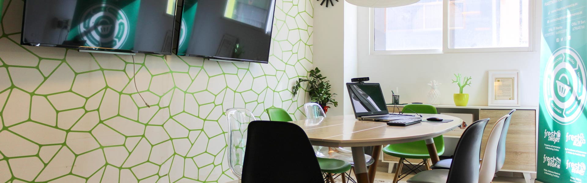 Sala de reuniones con mesa ovalada, muchas sillas y dos pantallas grandes en Tenerife.