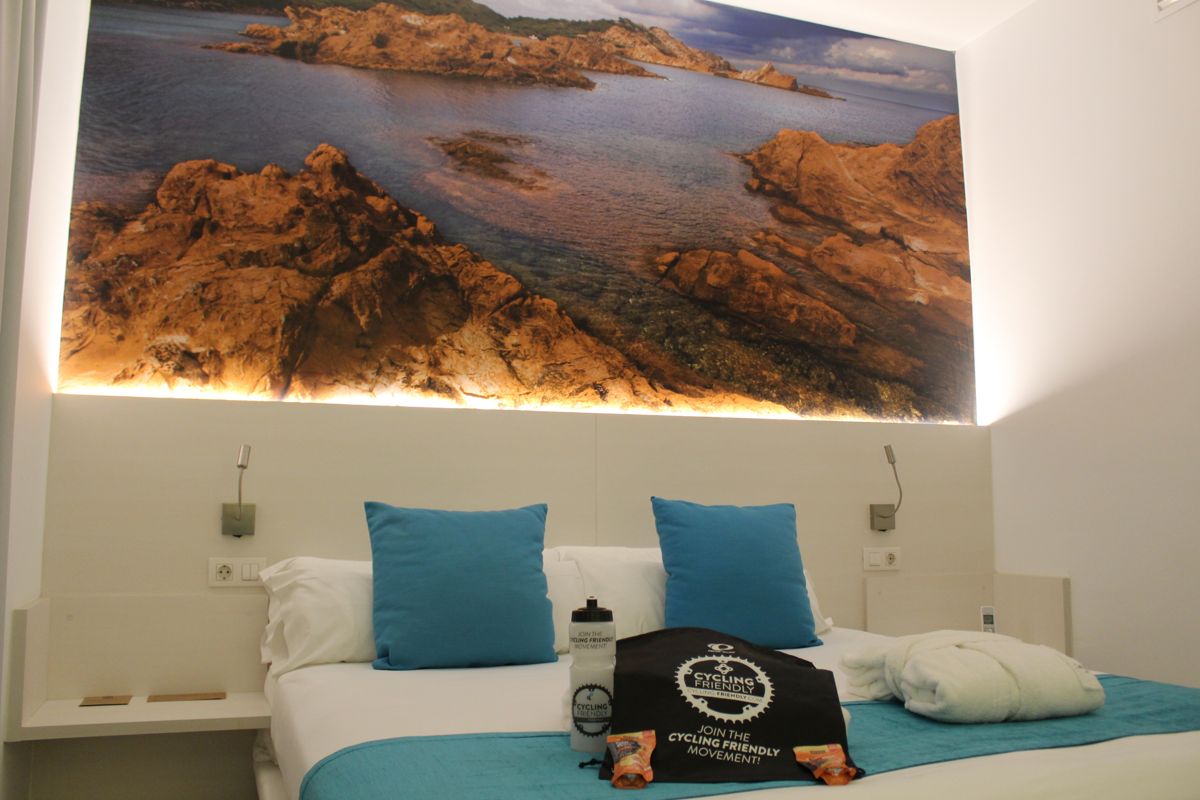 Cama con cojines azules y mural de un paisaje rocoso en un hotel de Tenerife.