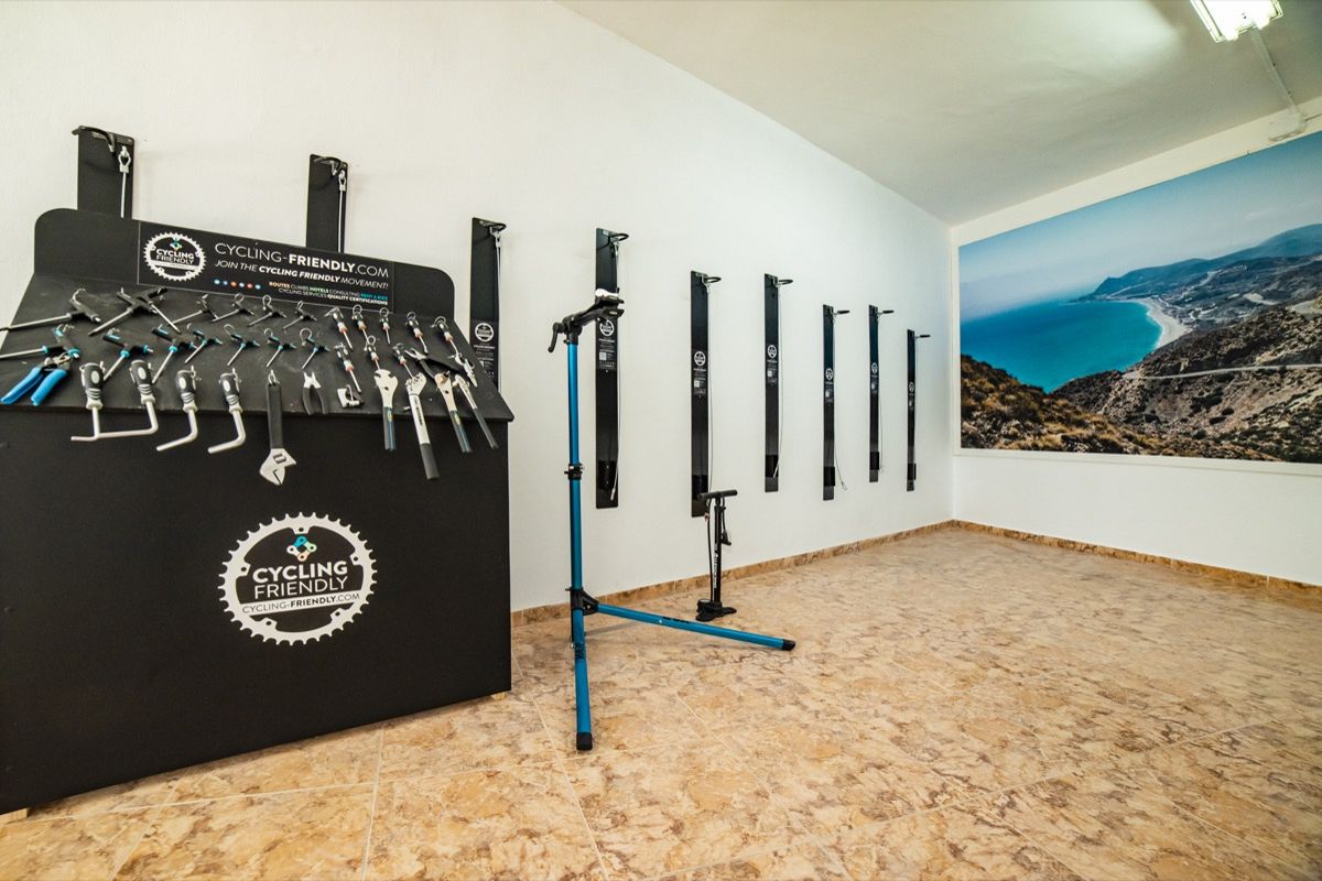 Herramientas de ciclismo en taller con mural costero en Tenerife.