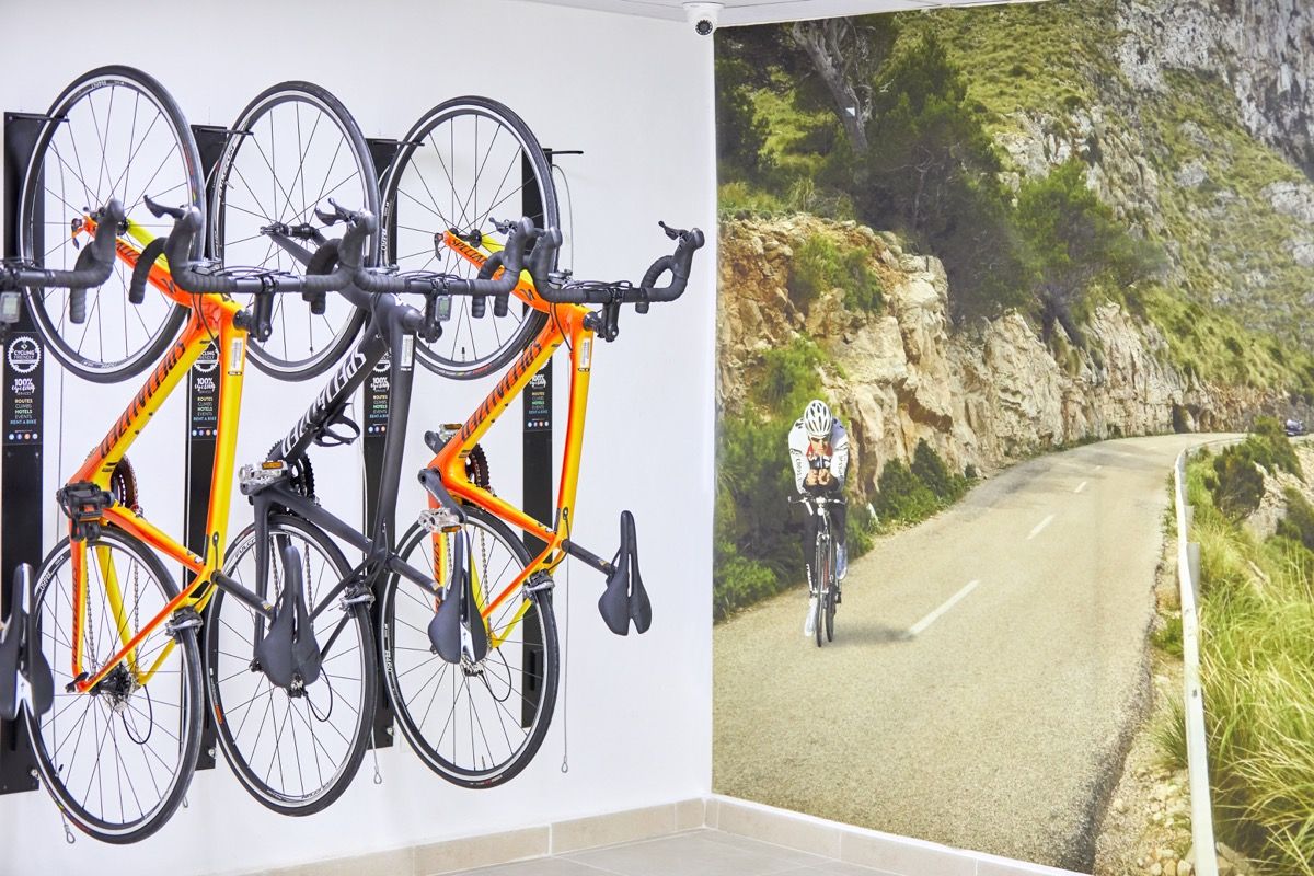 Bicicletas colgadas junto a mural de ciclista en carretera montañosa de Tenerife.